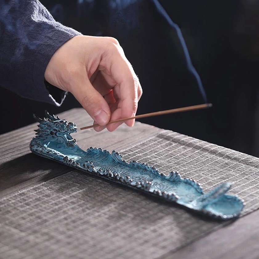 Dragon incense burner with incense stick placement on wooden tea table with woven placemat