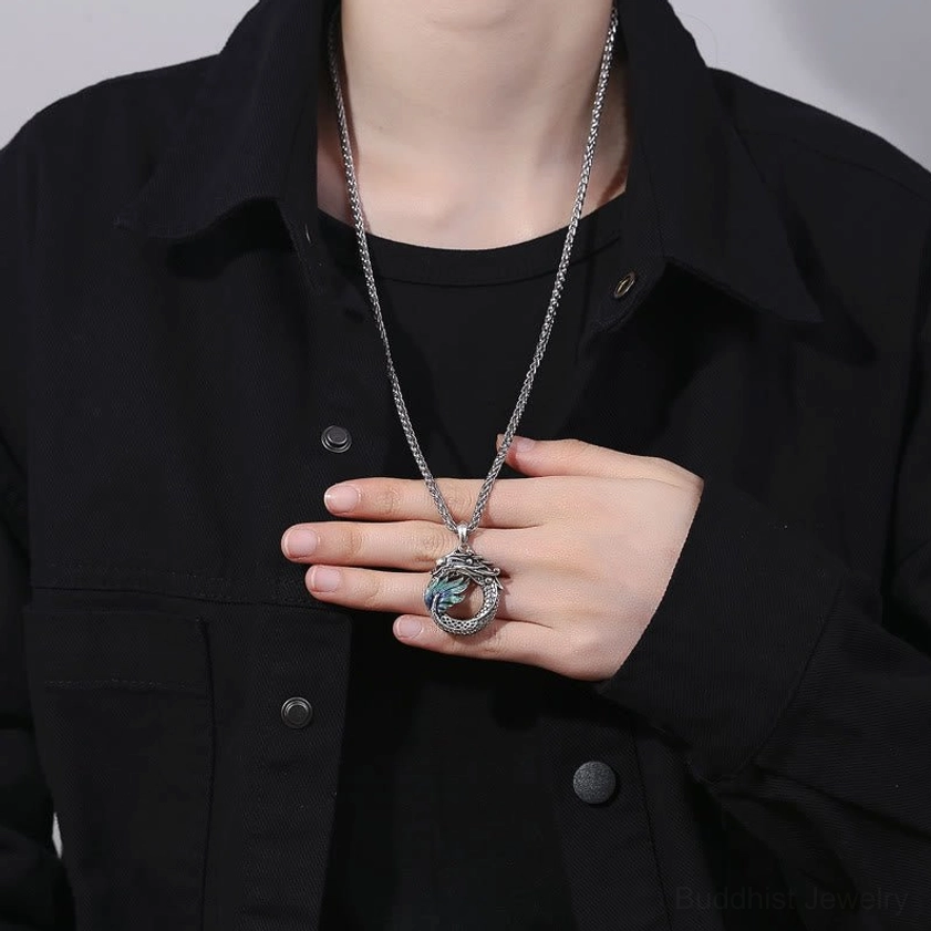 Dragon pendant necklace being worn on chest, silver chain with protective Buddhist symbol displayed on casual outfit
