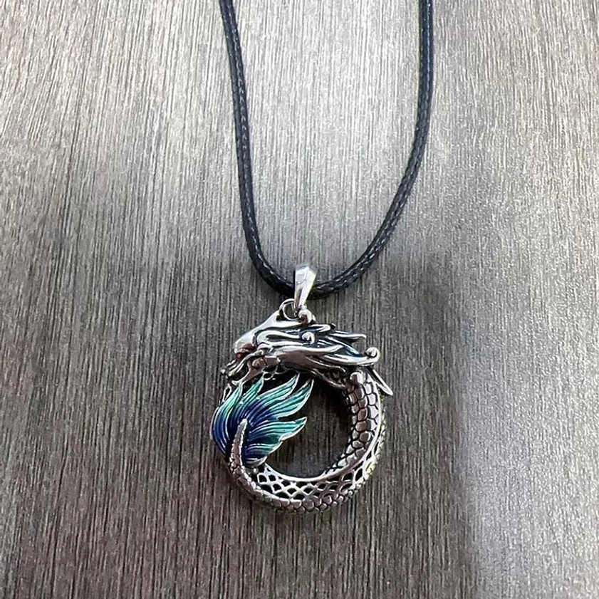 Buddhist dragon pendant with black leather cord, handcrafted copper dragon with teal enamel details on wood surface