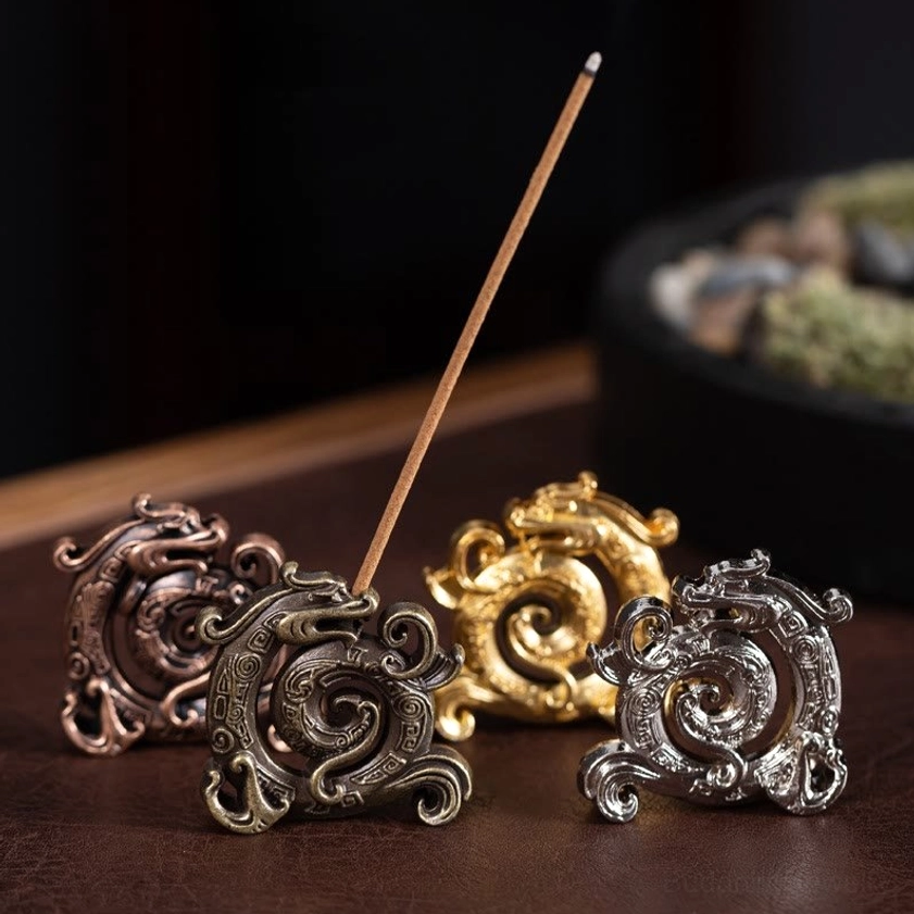 Collection of handcrafted dragon incense burners in multiple finishes - gold, silver, bronze, and dark red - displayed overhead on wooden surface
