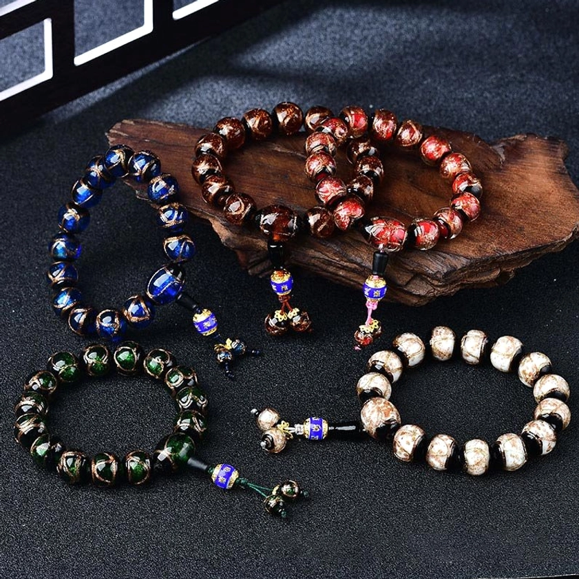 Assorted dragon vein agate healing bracelets displayed on wooden stand with enamel charms