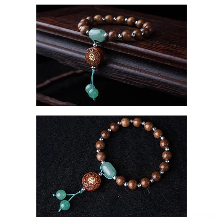 Compact dragon wood Buddhist bracelet side view with brown beads, small jade accent, Fu charm, and single tassel on dark wooden surface