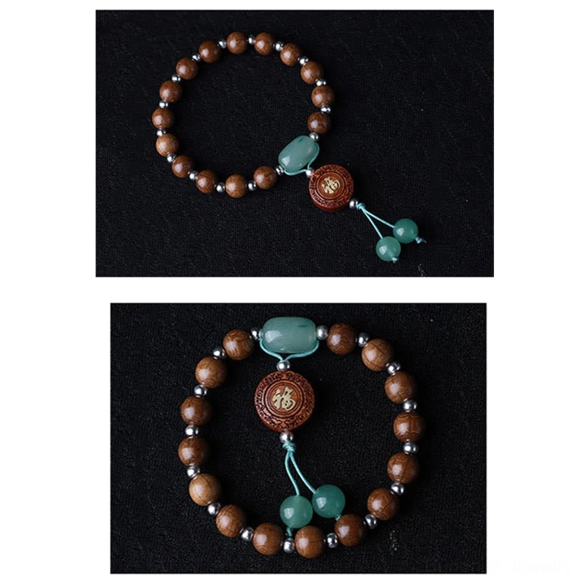 Top-down view of dragon wood Buddhist blessed bracelet with Fu charm and small dual jade tassels on clean black background