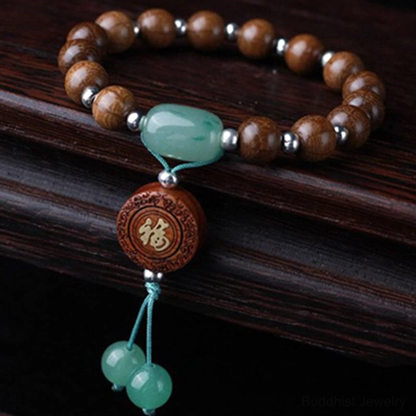 Abelia Biflora dragon wood Buddhist blessing bracelet with barrel jade, silver spacers, Fu charm, and decorative jade tassels on wooden table