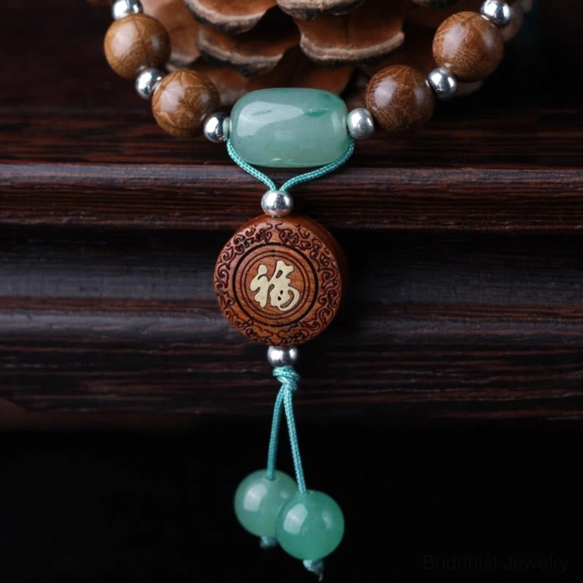 Natural abelia biflora wood Buddhist bracelet displayed on wooden table with pine cone, showing six-line pattern beads and jade tassel accent