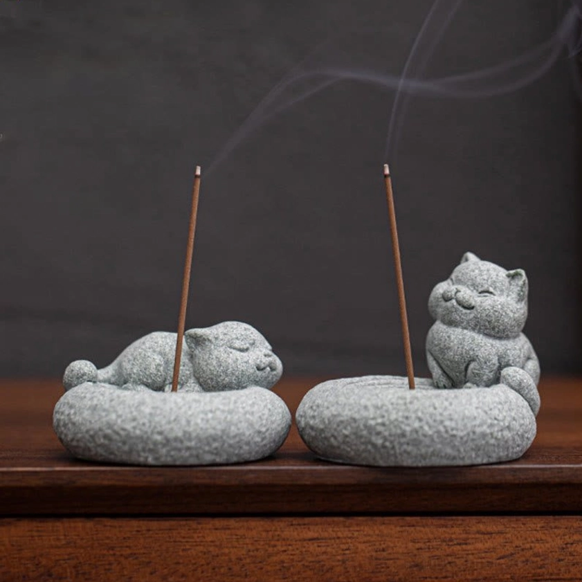 Two handcrafted cat incense burners overhead view on wooden table with lit incense