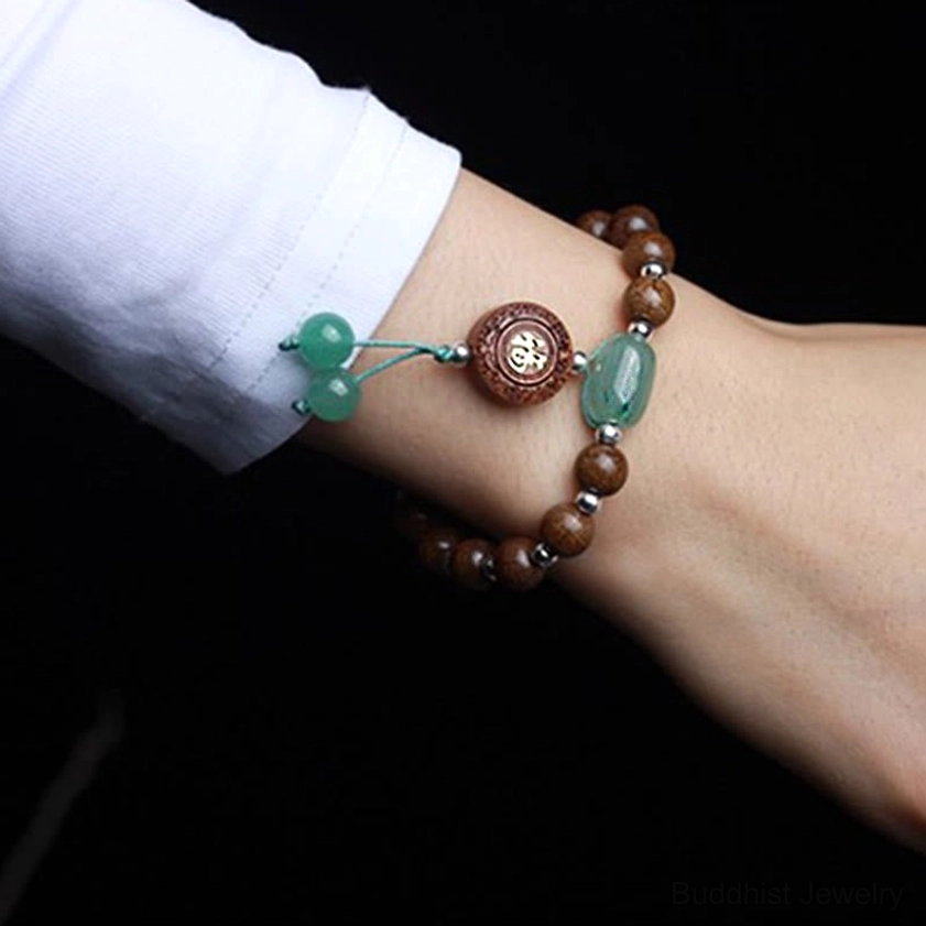 Two layered dragon wood Buddhist bracelets worn on forearm, showing paired meditation bracelets with jade accents and tassel details