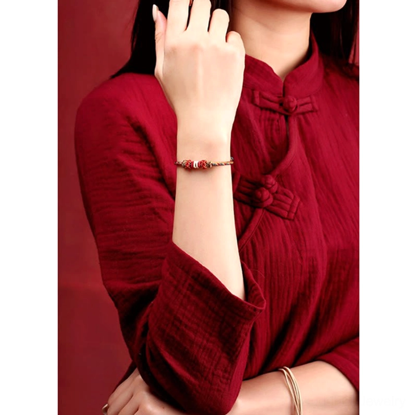 Buddhist protection bracelet worn on wrist showing slim red and gold tone weave traditional spiritual accessory