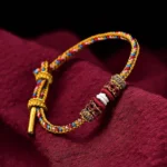Handmade Dunhuang lucky braided string bracelet multicolor woven design with decorative knots displayed on dark red fabric
