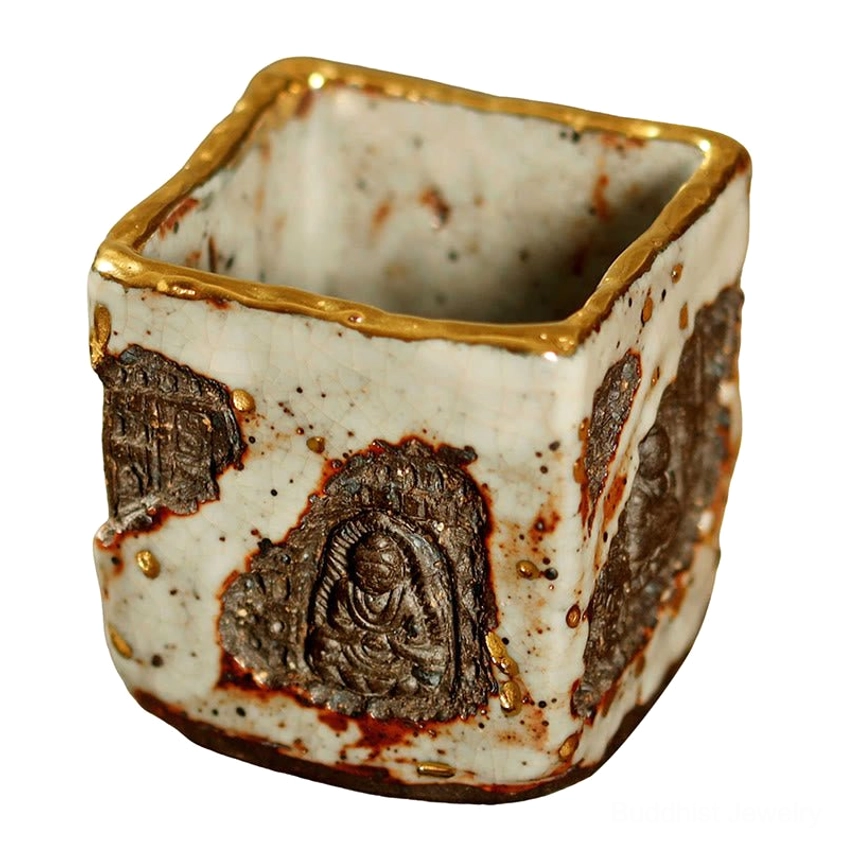 Dunhuang Buddhist Shino ceramic teacup front side view with central carved Buddha motif, gilded cup rim, and rusty brown glaze accents