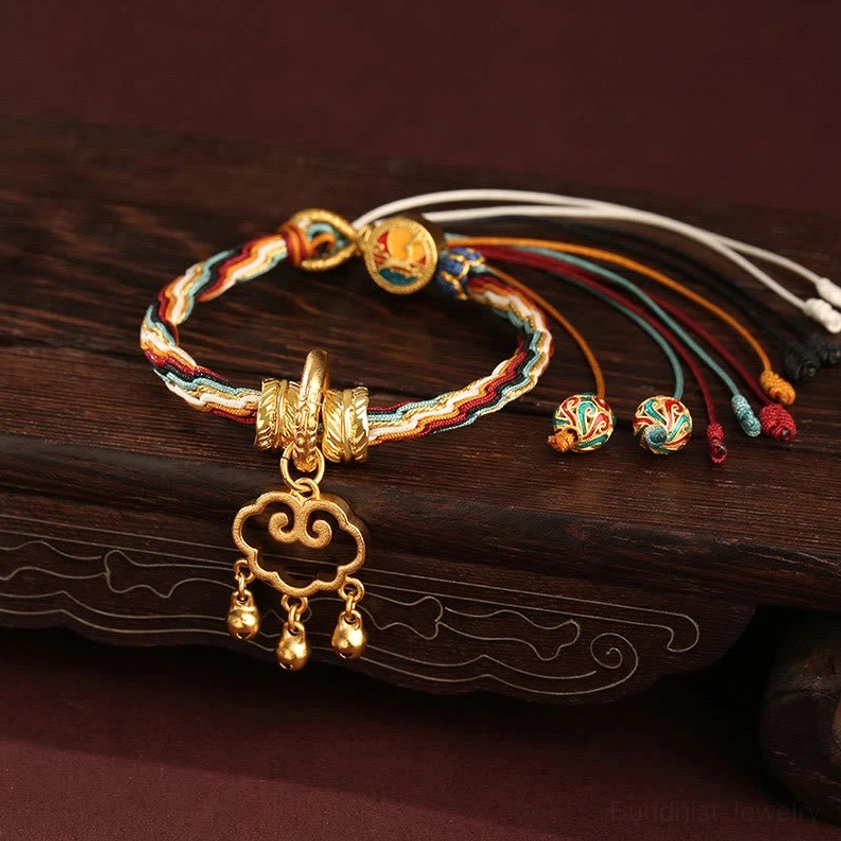 Dunhuang color multicolor braided Buddhist protection bracelet with ornate gold cloud lock pendant and tassel charms, flat lay view