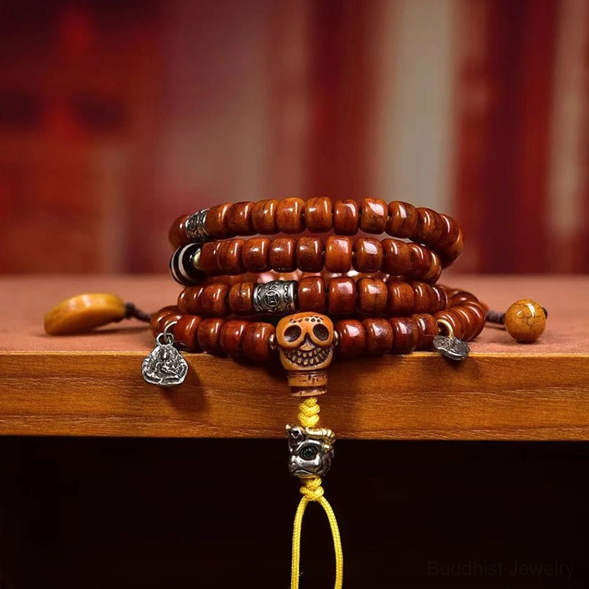 Close-up front view of brown barrel bone beads and Dzi amulet charm on Buddhist mala bracelet displayed on wooden shelf with loose beads