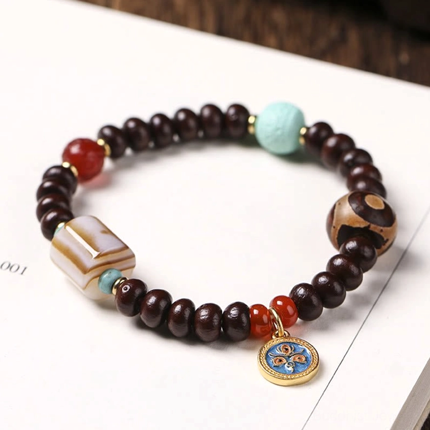 Detailed view of purple bodhi seed bracelet with three-eye dzi bead and agate stone on calligraphy paper