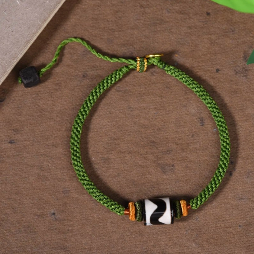 Back view of nine-eye dzi bead protection bracelet showing adjustable sliding knot and orange decorative details