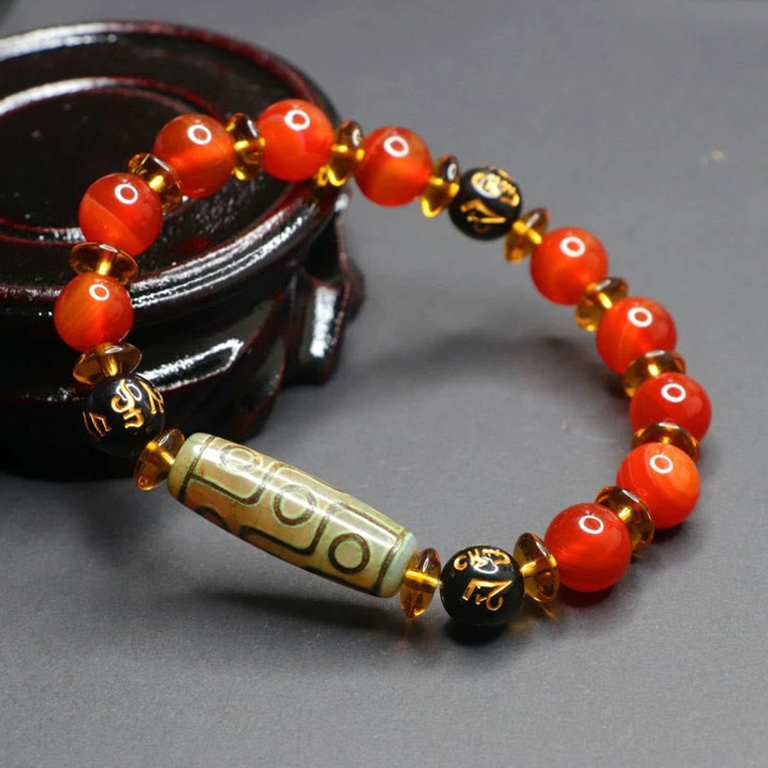 Close-up detail of om mani padme hum Buddhist bracelet showing dzi bead texture and engraved mantra beads