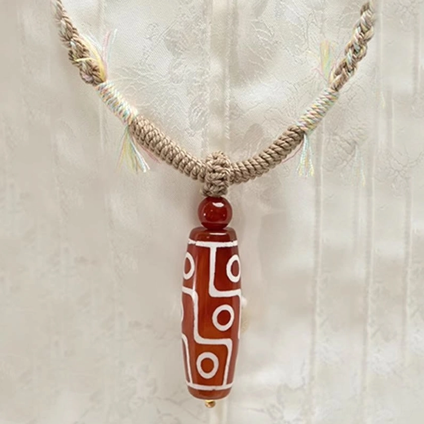 Nine-eye dzi bead pendant bracelet front close-up with distinct white nine-eye patterns on thin braided rope, spiritual protection symbol