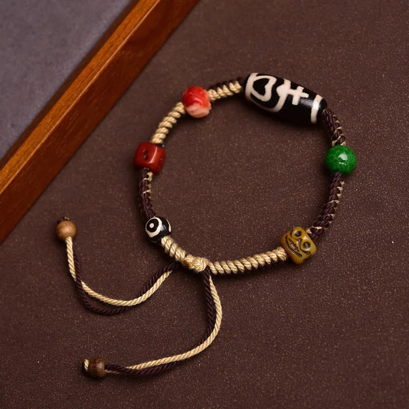 Complete nine-eye dzi bead bracelet with adjustable knots, mixed weave rope, multiple accent beads on dark wooden frame background