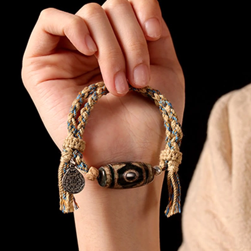Buddhist spiritual bracelet with engraved metal pendant held on palm, showcasing copper alloy accent details