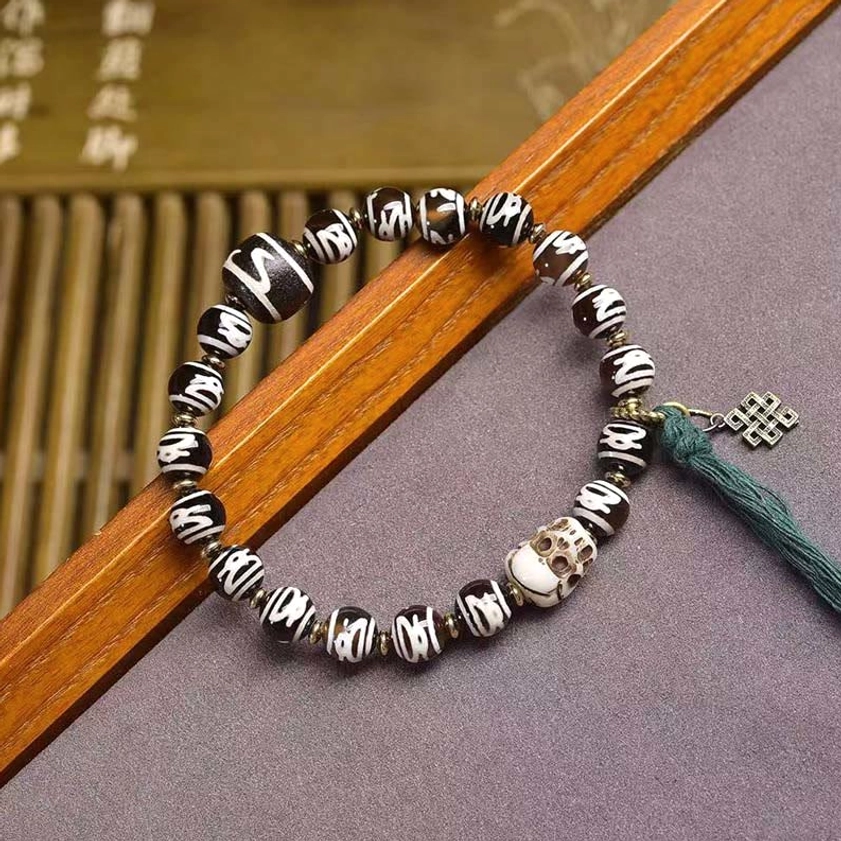 Buddhist dzi bead bracelet with authentic hand-painted black and white stripe pattern beads and green tassel detail