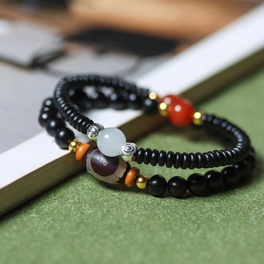 Close-up side view of double wrap Buddhist bracelet with stacked strands featuring ebony wood, sandalwood, and decorative bead accents