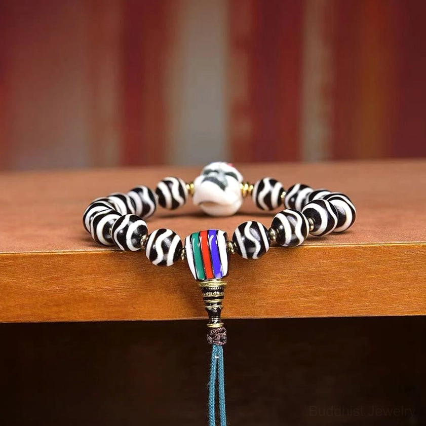 Close-up detail of dzi bead protection bracelet showing skull charm and gold spacer beads