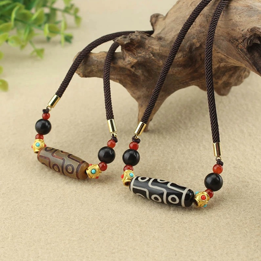Two Nine-Eye Dzi Buddhist protection necklaces displayed together - one brown and one black-white variant with natural stone accents