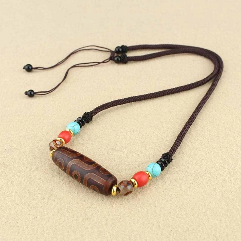 Single dzi bead Buddhist pendant necklace front view with adjustable pull-string cord and colorful agate spacer beads on plain background