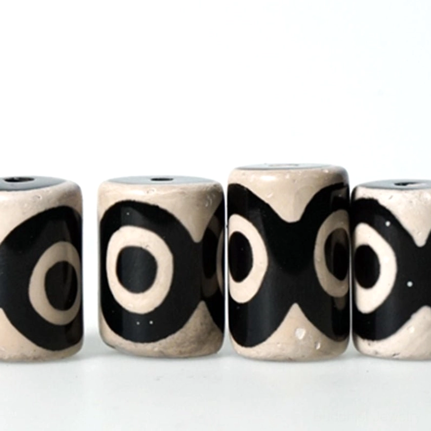 Flat lay collection of multiple hand-painted dzi beads with different eye patterns on white background