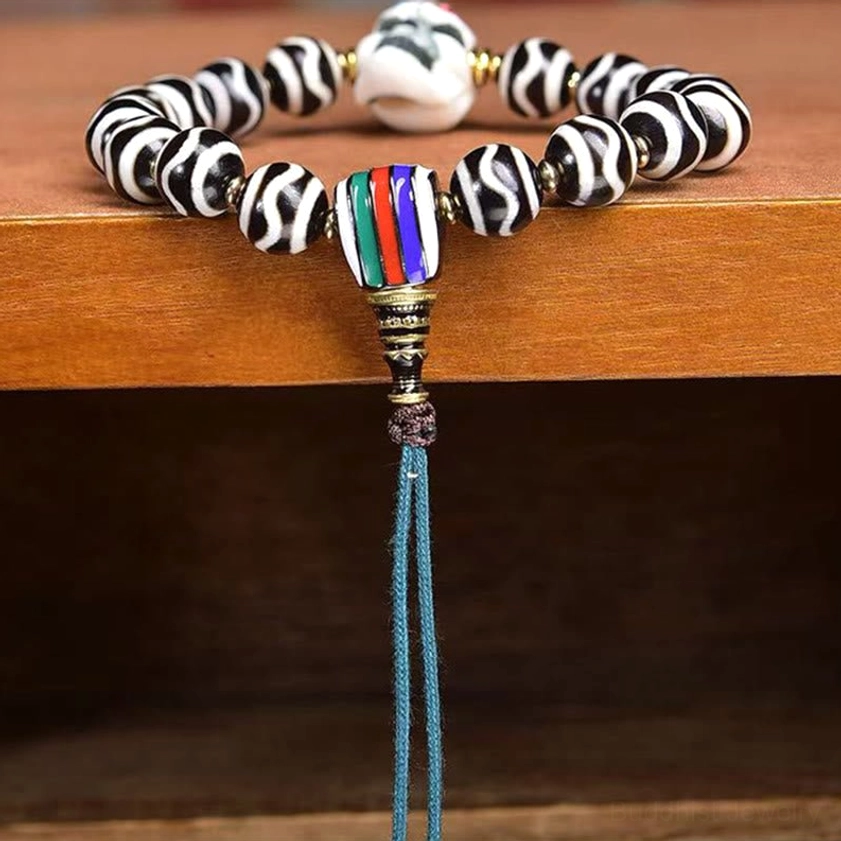 Full overhead view of dzi bead corpse forest lord bracelet with blue braided cord and skull charm on wooden table