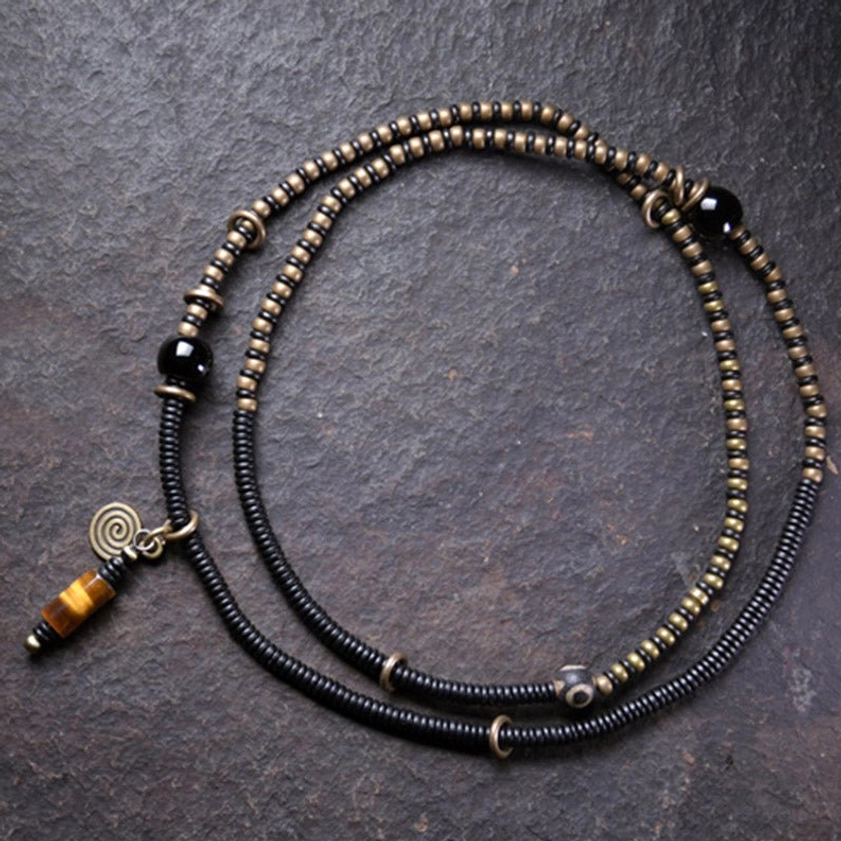 Hand-painted dzi bead and ebony wood bracelet necklace set oblique view dark background showing protective beads and copper accents
