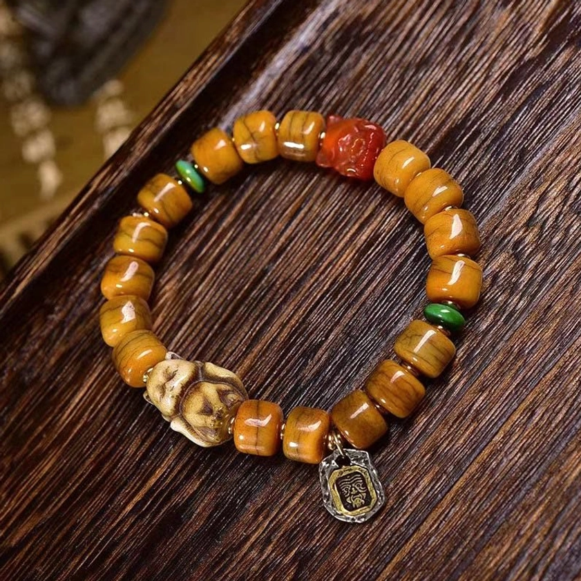 Buddhist bone bead bracelet with sacred dzi bead and fox charm, flat lay detail showing metal accents