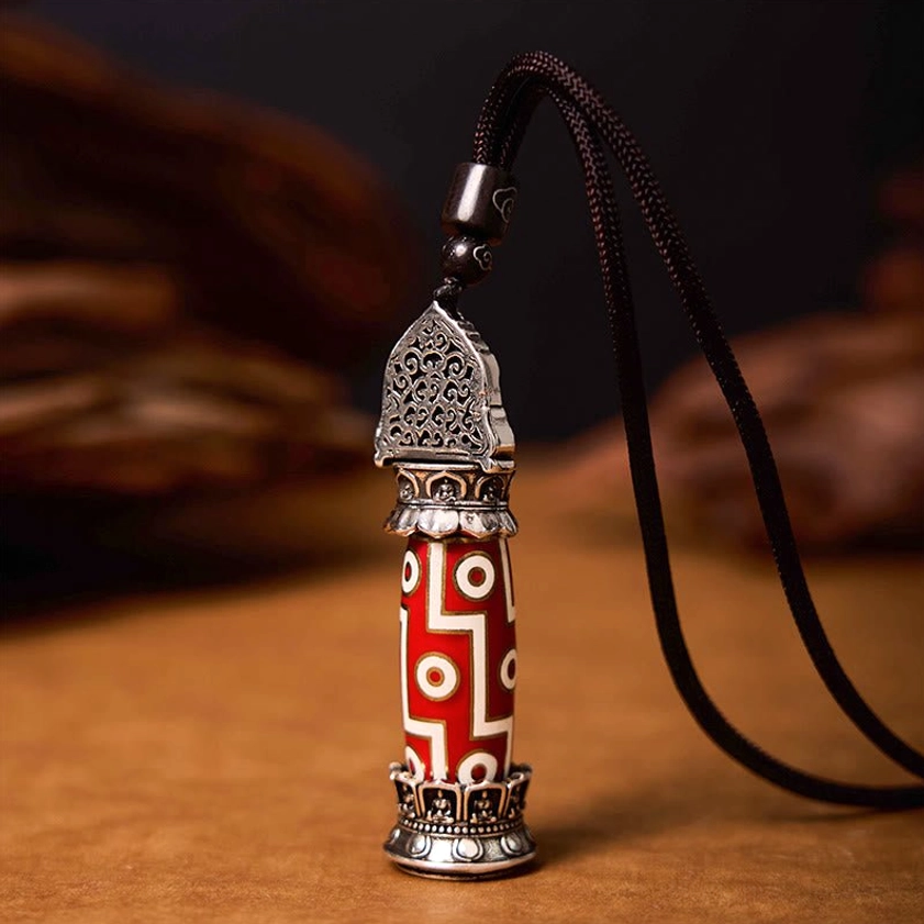Buddhist necklace pendant with Nine-Eye Dzi bead featuring hollow carved silver top and black braided cord