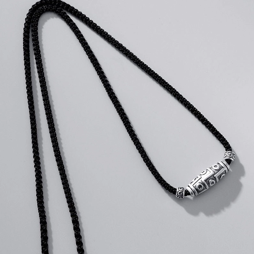 Buddhist dzi bead pendant necklace flat lay top-down view showing dual braided cords and full carved sacred geometry design