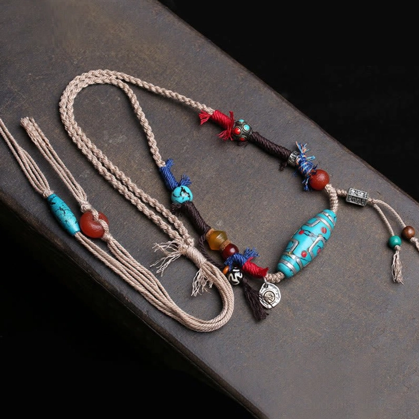 Tibetan Buddhist dzi bead necklace detail with red-blue woven tassels and decorative gemstone beads, handmade spiritual pendant