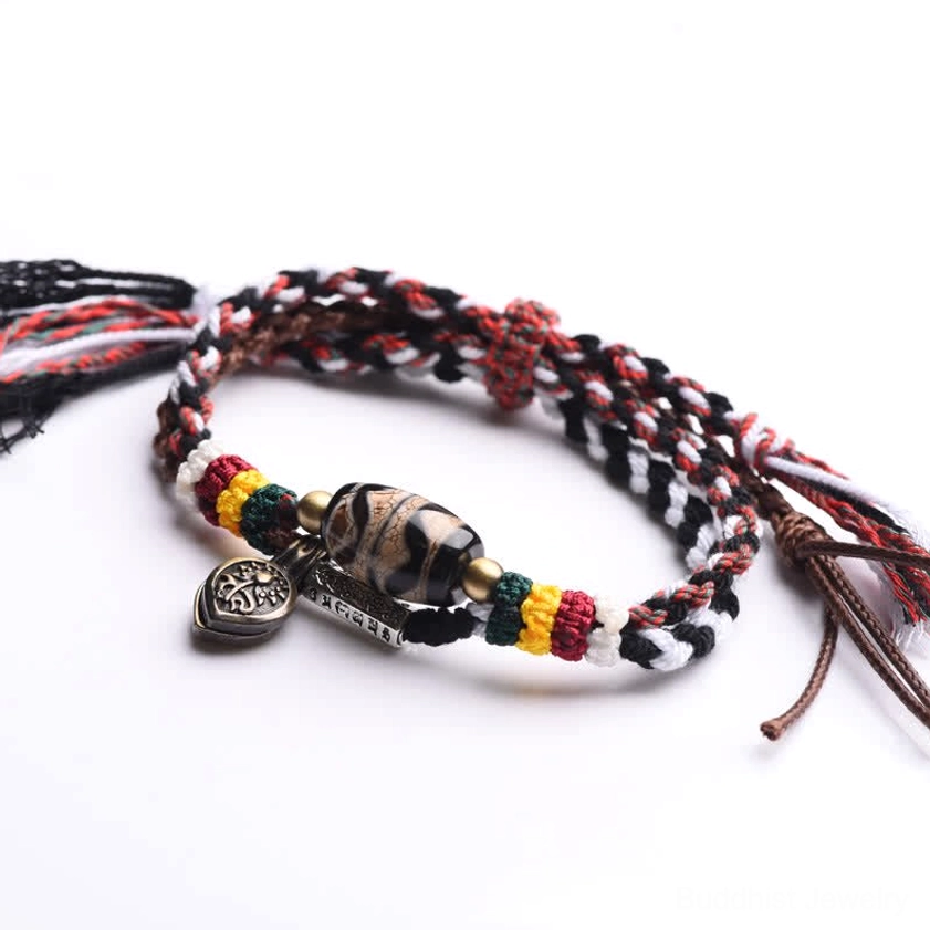 Multi-color braided rope dzi bead Buddhist bracelet with copper pendants and protective amulet beads close-up