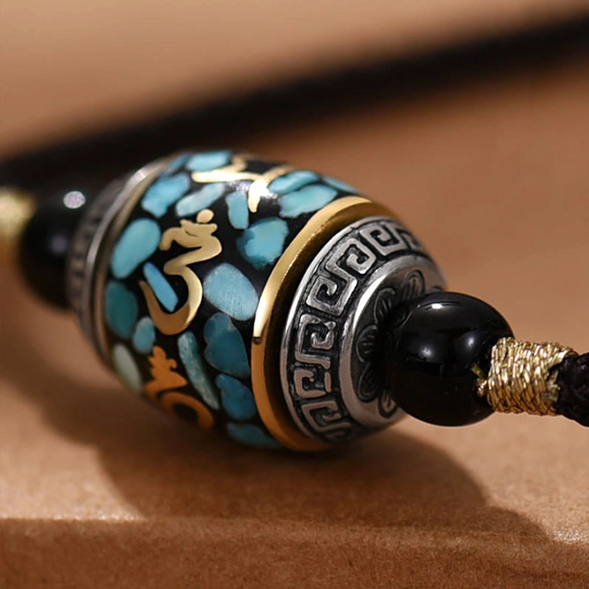 Close-up detail of sacred Dzi Bead pendant with Sanskrit symbols and turquoise inlay