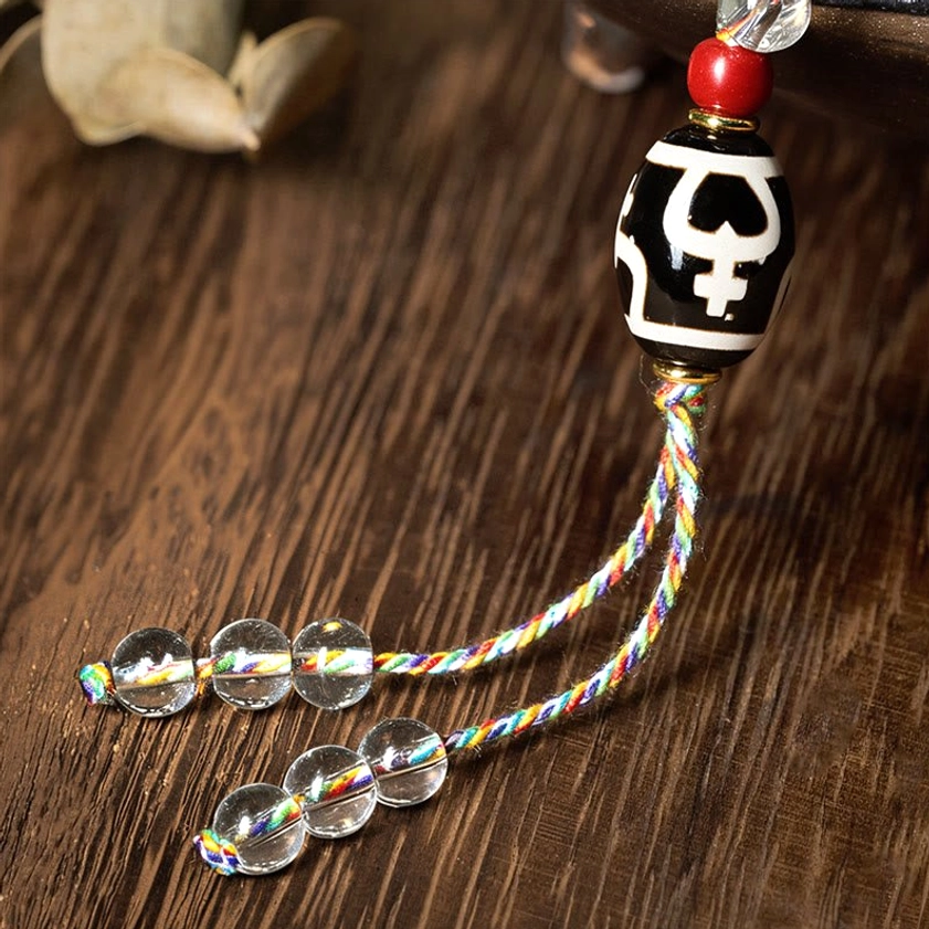 Close-up dzi pendant mala showing large black-white patterned bead and shiny crystal tassel