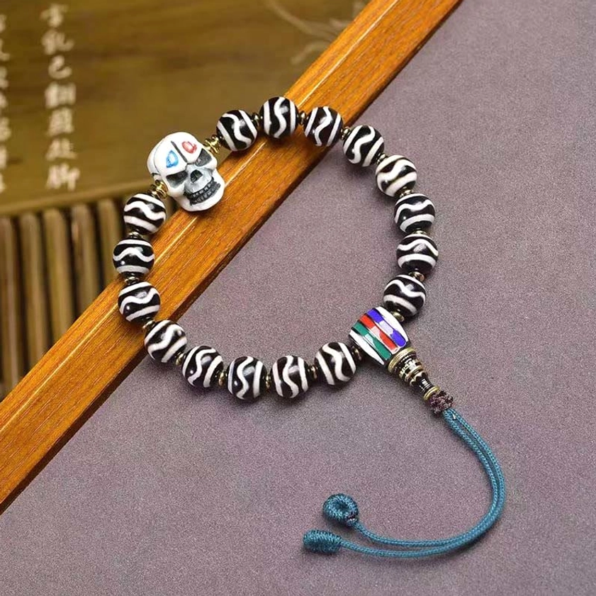 Dzi bead Buddhist protection bracelet with skull focal bead on calligraphy wooden backdrop