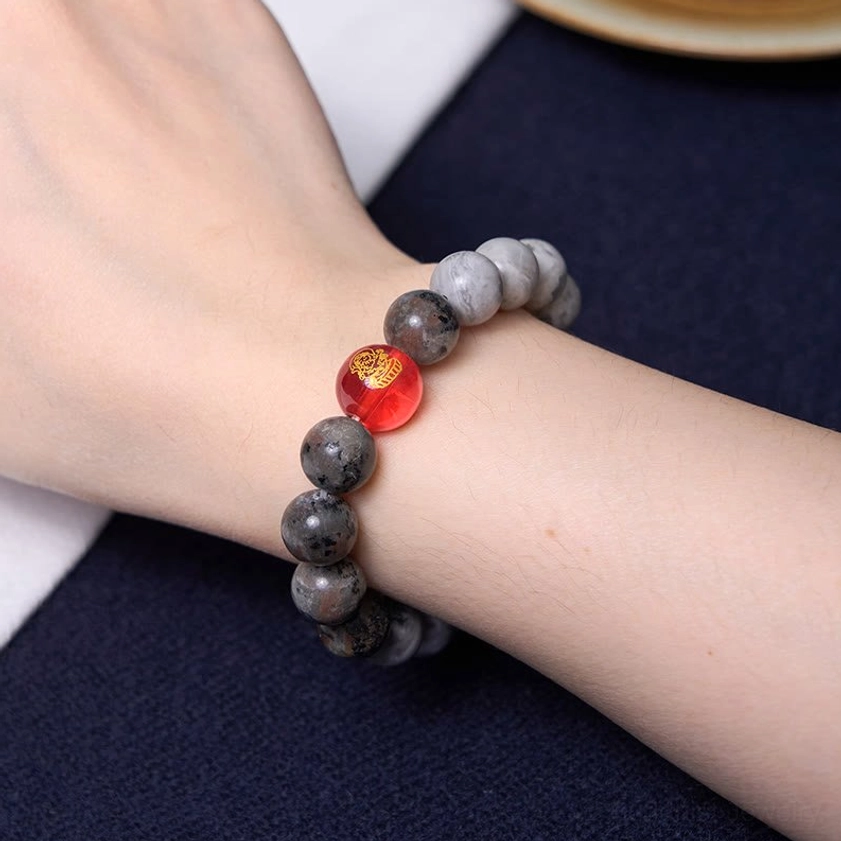Nine-eye dzi bead bracelet worn on wrist with mixed gray and engraved red bead showing real-life wear styling