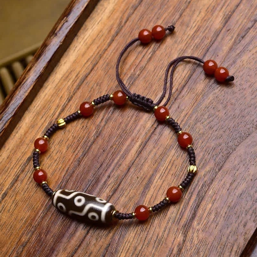 Single authentic dzi bead protection bracelet featuring brown woven rope, red agate beads, and central nine-eye dzi bead with metal spacers