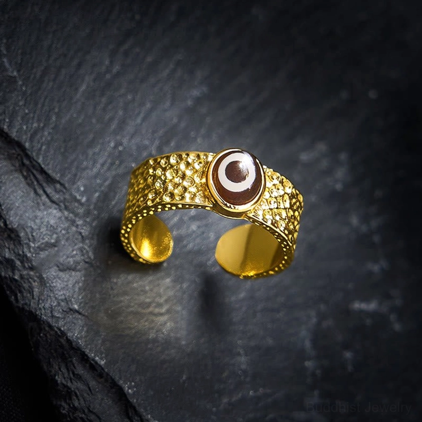 Adjustable dzi bead copper ring top-down overhead view showing intricate hammered gold band and brown-white sacred eye pattern