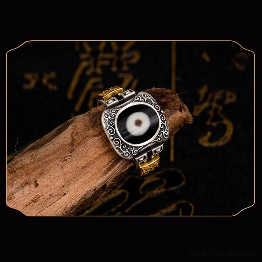 Hand-crafted Dzi bead ring in 925 sterling silver featuring square bead bezel and gold decorative ends, top right view on calligraphy background
