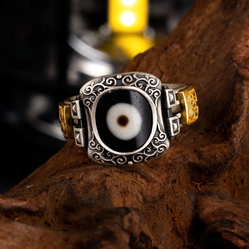 Buddhist Dzi bead protection ring in 925 sterling silver, top front view showcasing hand-painted single-eye bead and ornate scroll bezel with dual gold decorative elements