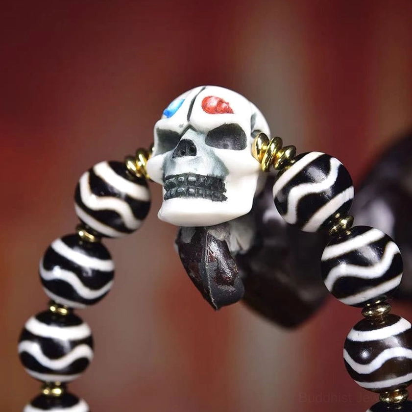 Macro photograph of handpainted dzi bead with 3D skull charm, striped pattern, and copper metal spacers