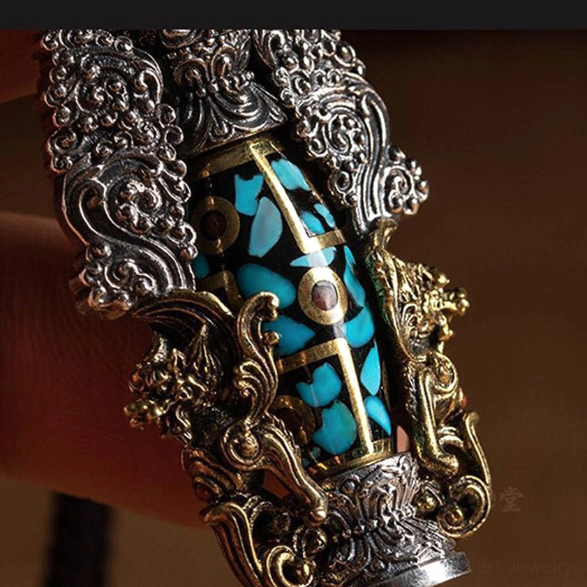 Extreme close-up of nine-eye dzi bead showing turquoise inlay detail, gold decorative accents, and intricate metal frame craftsmanship