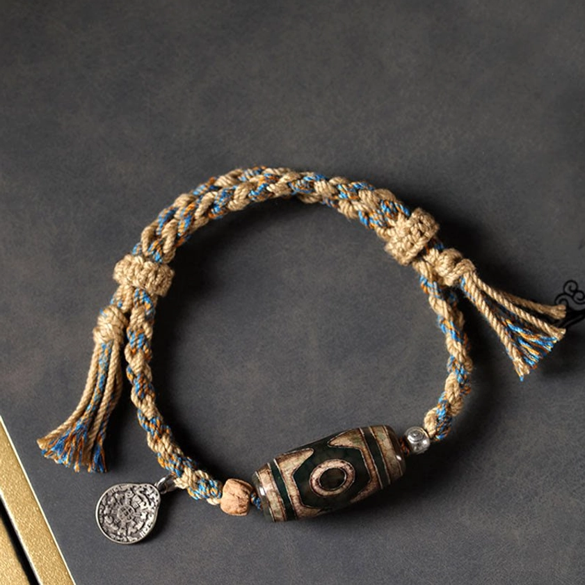 Buddhist dzi bead string bracelet with mixed woven cord and round metal pendant