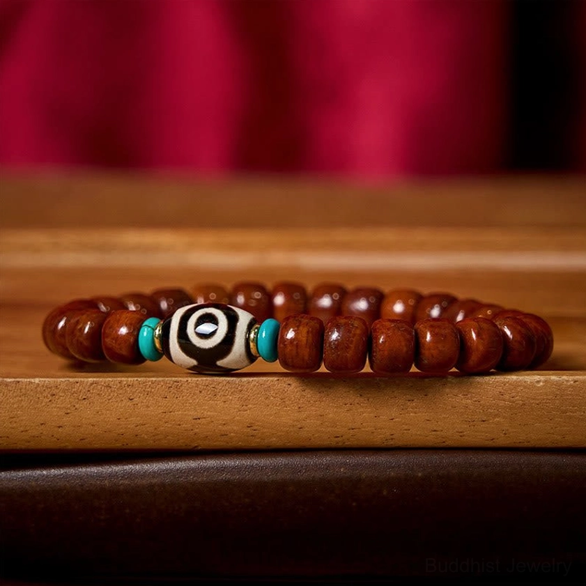 Three-eyed Dzi bracelet detail showing bone beads, Dzi bead pattern, Tibetan silver accents, and red thread design elements