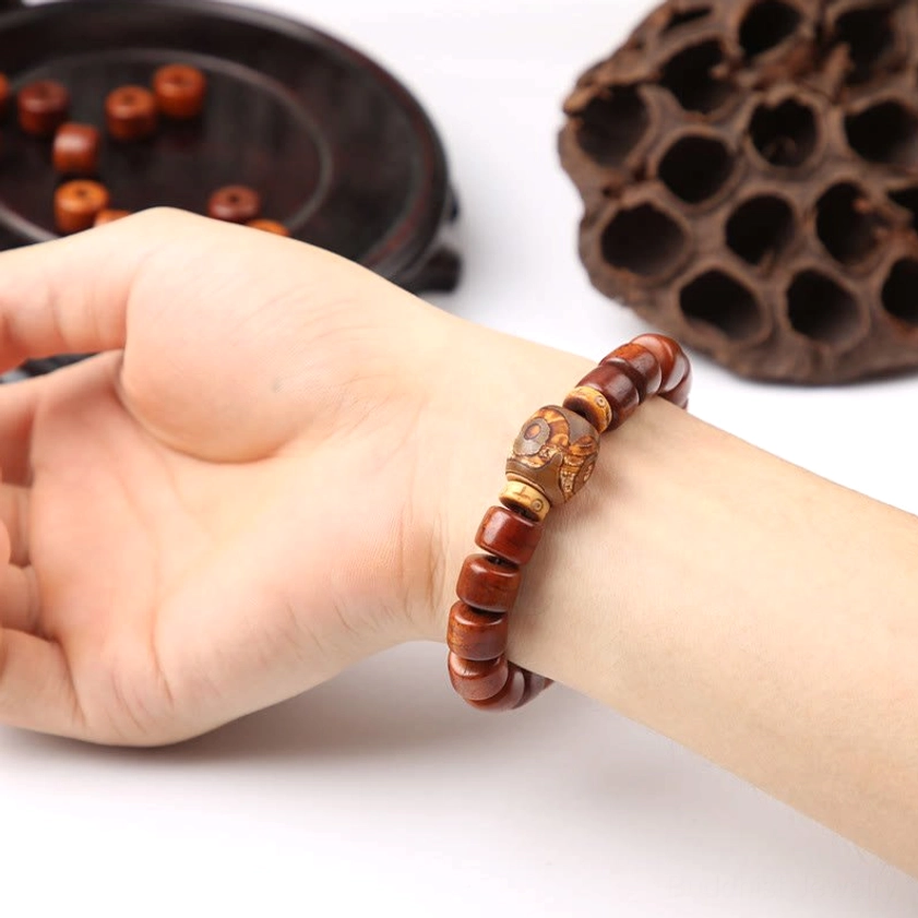 Wearing three-eyed Dzi bone bead bracelet on wrist with lotus decoration lifestyle shot