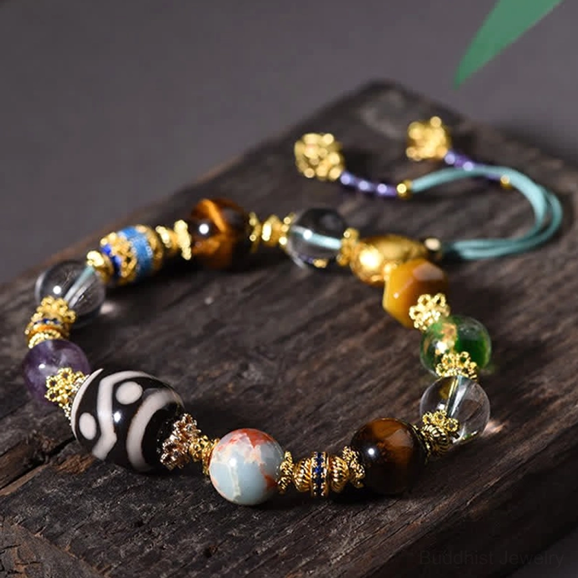 Hand-painted Dzi bead bracelet with amethyst and tiger eye stones on wooden tray showing detailed craftsmanship