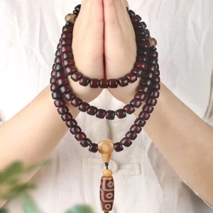Buddhist dzi mala bracelet with three-eye and nine-eye stones worn on wrist, showing jade spacer beads and protective amulet design for daily wear and meditation